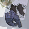 Children's outfit with navy pants and black patterned shirt on a light gray surface.