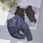 Children's outfit with navy pants and black patterned shirt on a light gray surface.