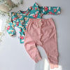 Children's outfit with floral top and pink pants on a light background
