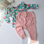 Children's outfit with floral top and pink pants on a light background