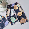 Navy baggy trousers with colorful abstract patterns on a light gray surface.