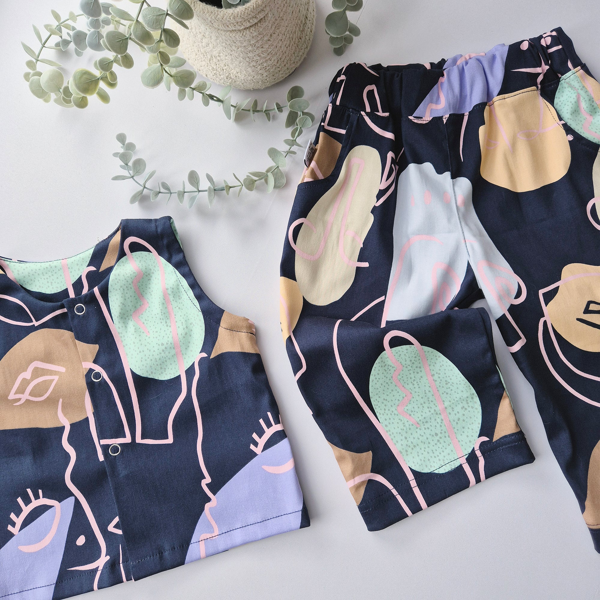 Patterned pants and top on a light surface with greenery in the background