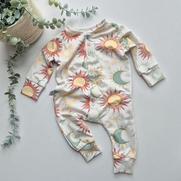 Baby onesie with celestial pattern on a light gray background