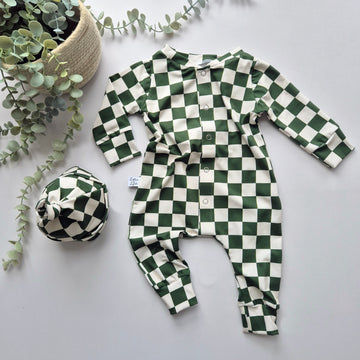 Green and white checkered baby outfit with matching hat on a light gray background with eucalyptus leaves.