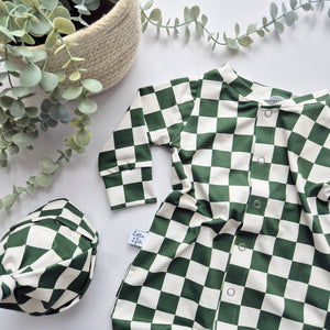 Green and white checkered outfit with matching hat on a light background with plants.