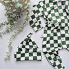Green and white checkered baby outfit with matching hat on a light background