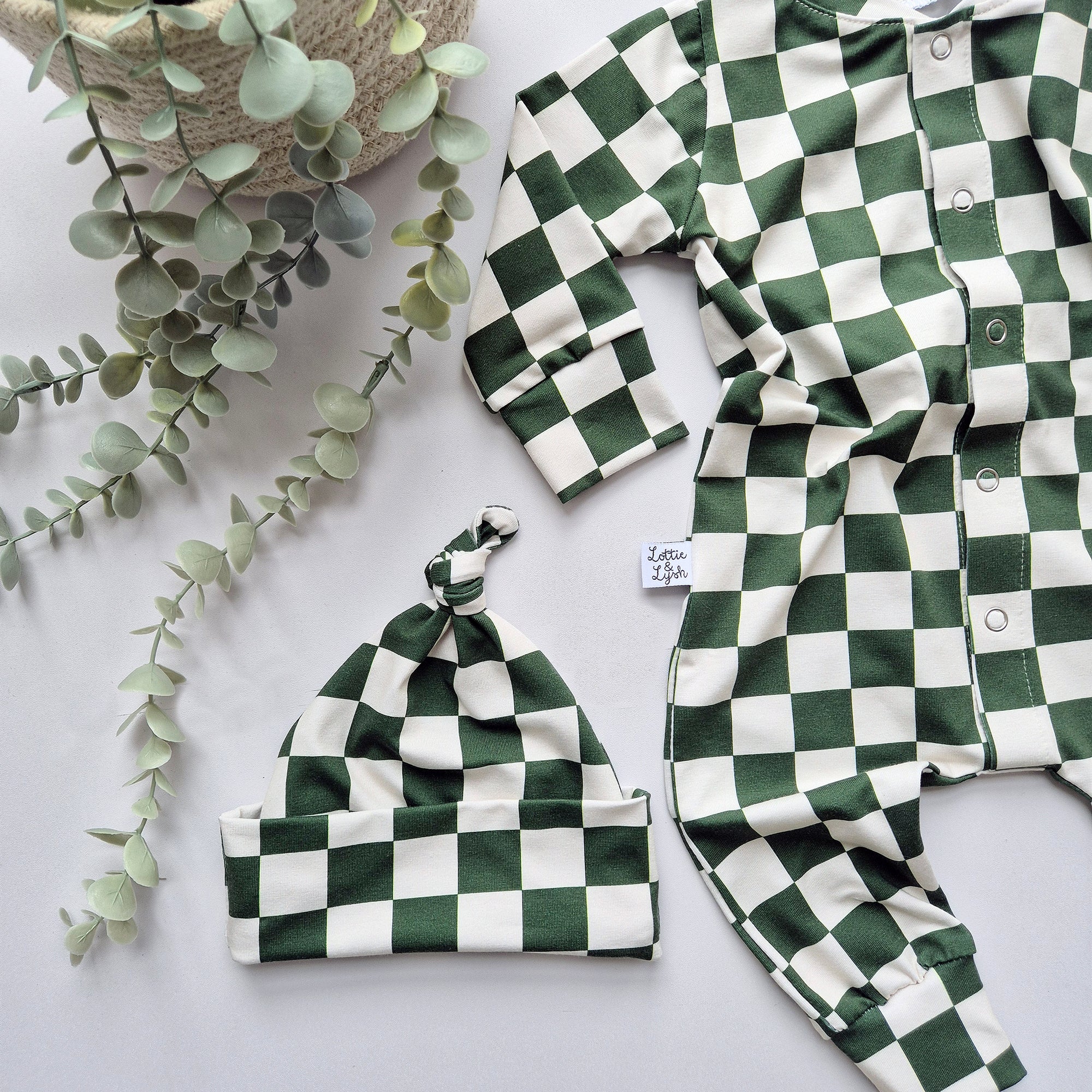 Green and white checkered baby outfit with matching hat on a light background