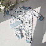 Baby onesie with text and matching headband on a light surface with greenery.