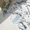 Baby outfit with 'Welcome Little One' text and paw prints on a light background