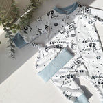 Baby outfit with 'Welcome Little One' text and paw prints on a light background