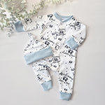 Baby outfit set with white onesie and hat with text and footprints on a light gray background.