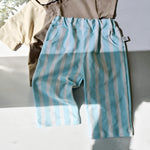 Blue and white striped pants with a beige shirt on a white surface