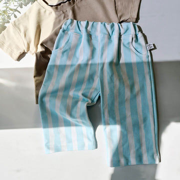 Blue and white striped pants with a beige shirt on a white surface