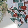 Patterned fabric outfit with green and brown design on a white surface with a plant.