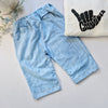 Light blue denim look trousers on a light gray surface with a white swetshirt featuring black shacka good vibes decal.