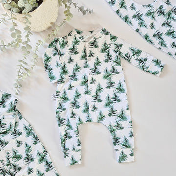 White babygrow with green trees.