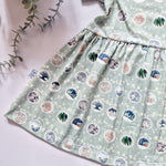 Girls Christmas Day outfit featuring Christmas Baubles with different festive scenes against a green background 