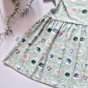 Girls Christmas Day outfit featuring Christmas Baubles with different festive scenes against a green background 
