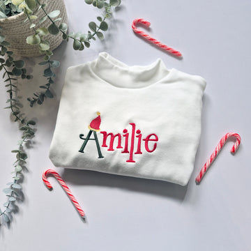 White sweatshirt with 'personalisation' embroidered on it, surrounded by candy canes and eucalyptus leaves.
