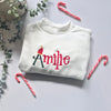 White sweatshirt with 'personalised' embroidery surrounded by candy canes and eucalyptus leaves on a light background