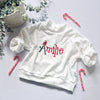 White sweatshirt with 'personalised' embroidery on it, surrounded by candy canes and greenery on a light background