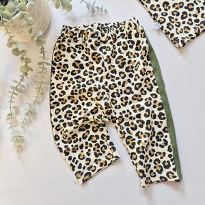 Leopard print pants on a light background with a plant and hat.