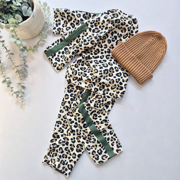 Leopard print tracksuit with green stripes and a brown beanie on a light background