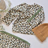 Leopard print outfit with green trim and a brown beanie on a light background