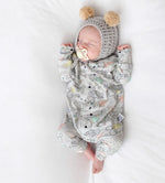 Newborn baby in a patterned outfit and knitted hat with pom-poms on a white background