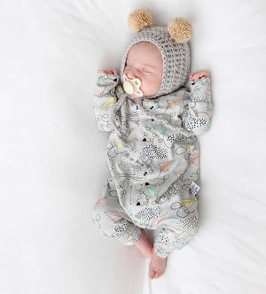 Newborn baby in a patterned outfit and knitted hat with pom-poms on a white background