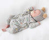 Newborn baby wearing a paper planes print romper and wearing a matching hat on a white background