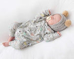 Newborn baby wearing a paper planes print romper and wearing a matching hat on a white background
