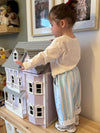 Child playing with a dollhouse in a home setting