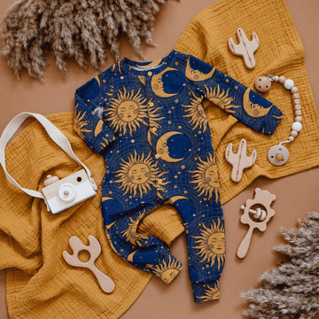 Baby onesie with celestial pattern on a yellow blanket with toys and decor