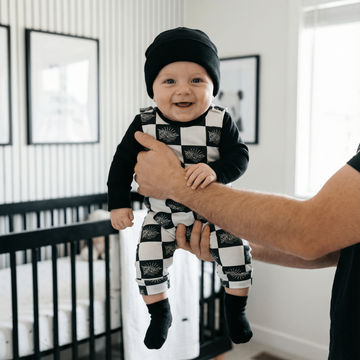 baby boy wearing black and white stay salty dungarees
