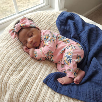 baby girl weraing tiger print babygrow and matching bow headband