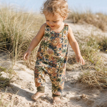 toddler boy on the beach wearing earthy celestial print handmade dungarees