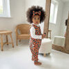 Child wearing a colorful outfit with a leopard print pattern in a bright room.