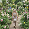 Little girl walking through a garden wearing a bunny bodywarmer with white tail.