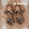 twin newborn girls wearing burnt floral sleepsuits and matching headbands