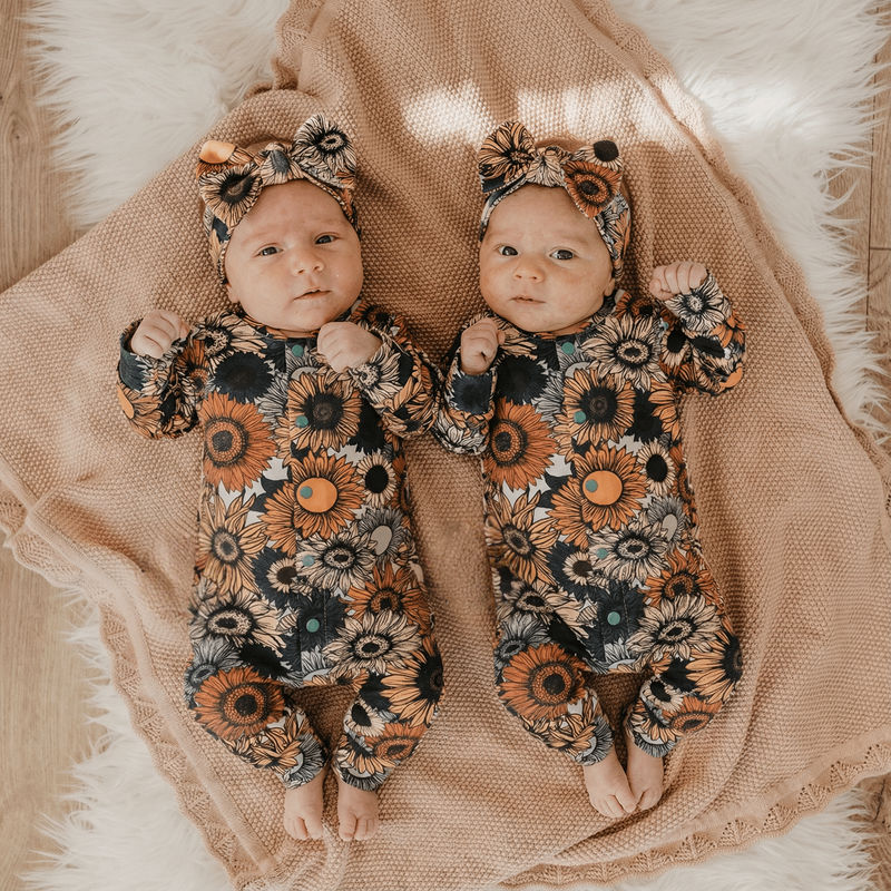twin newborn girls wearing burnt floral sleepsuits and matching headbands