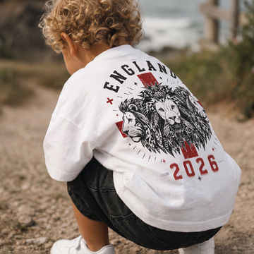 Child wearing a white sweatshirt with a lion design and 'England 2026' text outdoors.