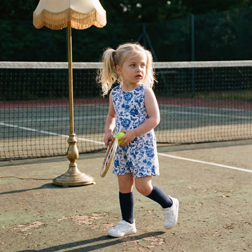 little girl wearing bow back white and blue floral short romper
