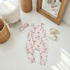 Baby romper with flamingo pattern on a light wooden floor.