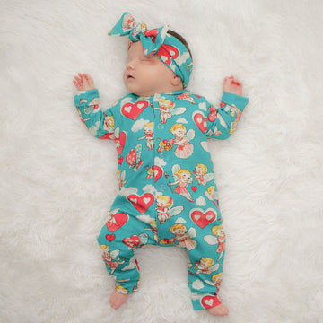 sleeping baby girl wearing a blue cherubs printed babygrow and matching headband set