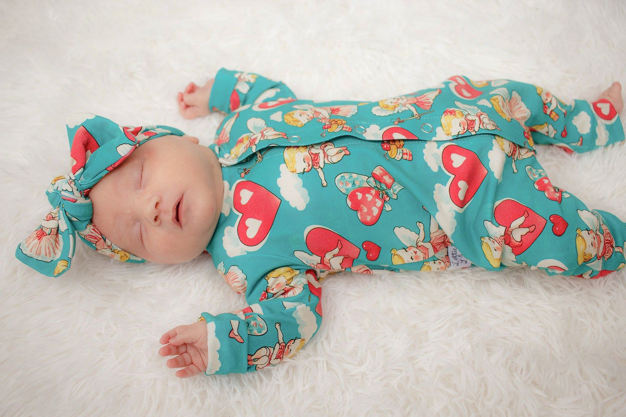 New baby girl wearing Lottie & Lysh cherubs baby romper with bow turban