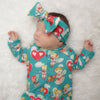 Sweet sleeping newborn baby girl wearing a cherubs printed baby romper with matching bow headband