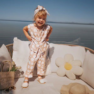 Child in a floral outfit sitting on a couch with a scenic background