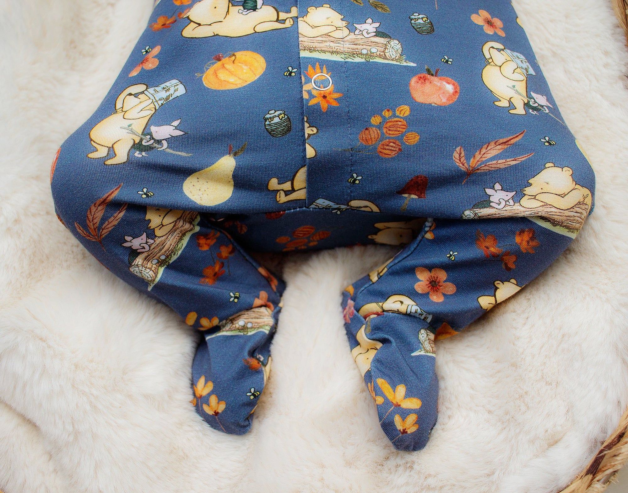 Winnie the pooh footed babygrow featuring illustrations of winnie the pooh and piglet.