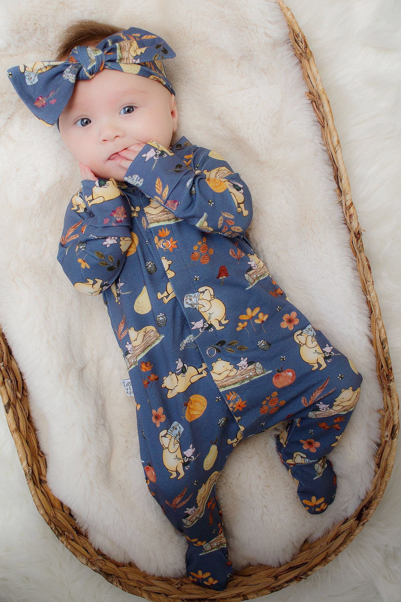 baby girl wearing blue winnie the pooh sleepsuit and matching headband